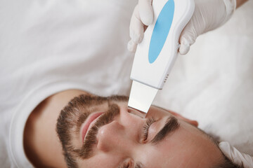 Cropped close up of a male face during ultrasound skin cleanse procedure at beauty salon