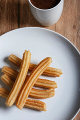 Fototapeta na wymiar Churros with chocolate on wooden background. Isolated and vertical image