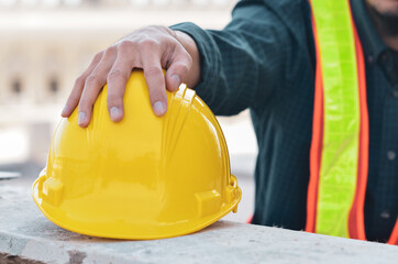 Yellow safety helmet in the hands of a builder