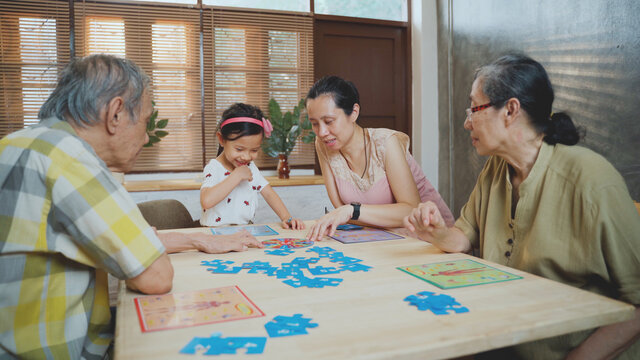 Multi Generation Of Asian Family Play Board Game Together, Happy Family Time Of Daughter Mother And Grandparent Playing In Living Room At Home On Holiday