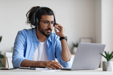 Distance Learning. Western Man In Headphones Studying Online With Laptop At Home