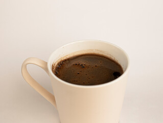 A mug of strong hot black coffee with foam in a white mug. The view from the top