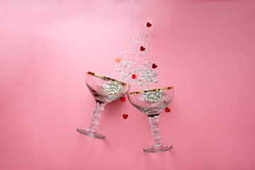 two  retro champagne glasses with star-shaped confetti splashes. Happy new year, merry christmas. Happy Valentine's Day. Pink background