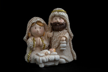 Fototapeta premium Representation of a Christmas nativity scene with the figures of baby Jesus, Mary and Joseph on a black background. Christmas concept.