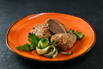 Meat pot on an orange plate. Hearty European lunch