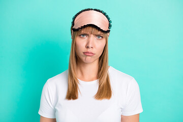 Photo of sad exhausted young girl unhappy disappointed face wear white sleepwear mask isolated teal color background