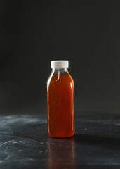 
Fresh fruit drink from berries or freshly squeezed juice in a disposable plastic bottle with a white cap on a dark background