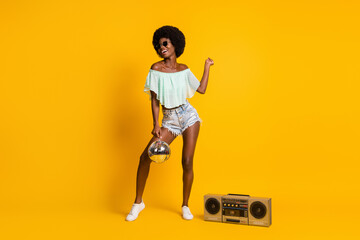 Full length body size photo of black skinned girl boombox dancing at summer party with disco ball isolated on bright yellow color background