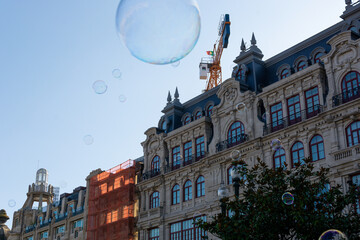Fototapeta na wymiar Big soap bubble and Porto city in the background. Aliados Avenue.