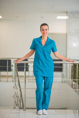 Young female doctor in blue uniform standing at the stairs