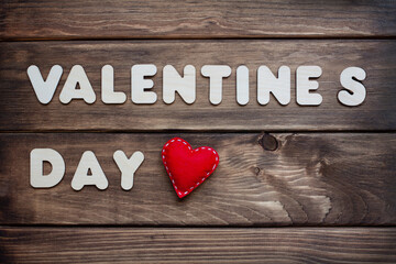 Valentine` s Day vintage concept with red felt heart on wooden texture. Plywood letters on a grunge surface. 