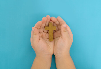 child's hands with Wooden Christian cross