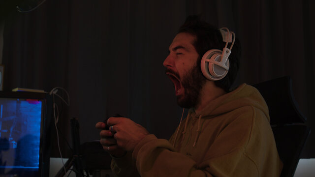 Male gaming with a game pad screaming and celebrating erratically