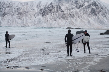 Arctic surfers going by beach after surfing