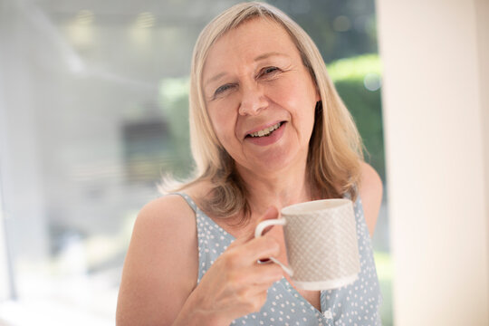 Portrait happy senior woman drinking tea at sunny window