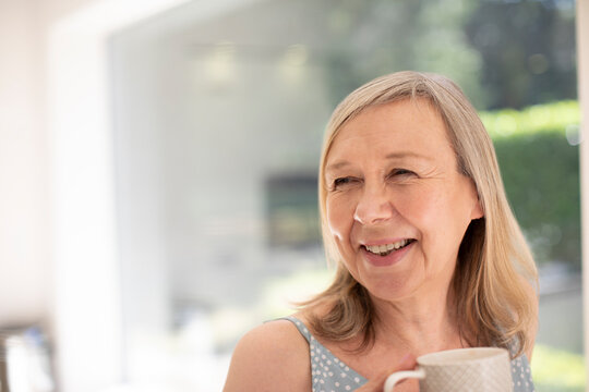 Portrait happy senior woman drinking tea at home