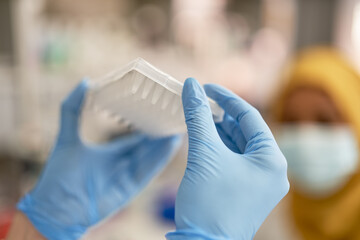 Close up scientist in rubber gloves holding specimen tray