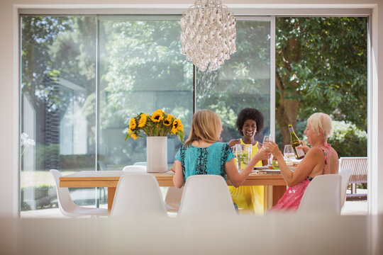 Happy senior women friends enjoying luncheon with wine at dining table