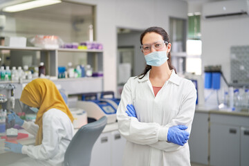 Portrait confident female scientist in face mask and rubber gloves