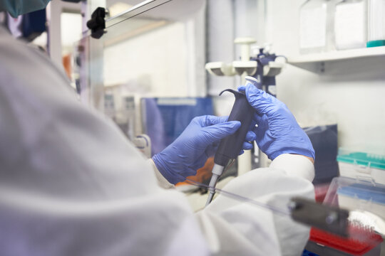 Close up scientist using pipette under fume hood in laboratory