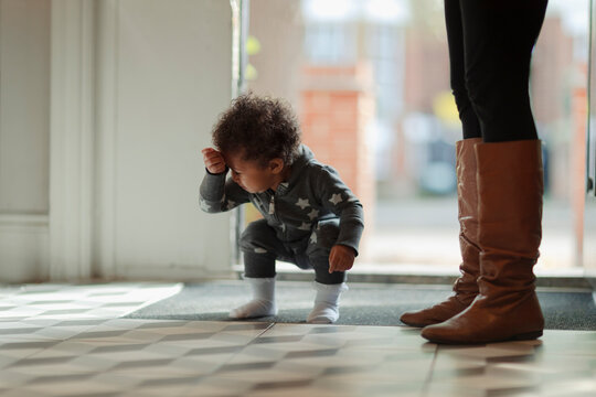 Cute baby girl in pajamas crouching at front door