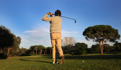 man playing golf in the course hitting the ball with swing