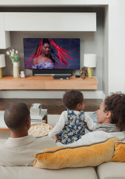 Family watching TV on living room sofa
