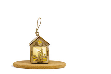 Christmas decorations, made of natural material, wooden carved house on a cork stand, on a white isolated background. Close-up, selective focus, copy space