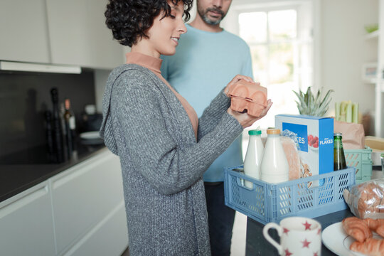 Couple Unpacking Groceries At Kitchen Counter