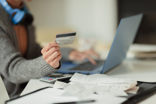 Close up woman with credit card paying bills online at laptop