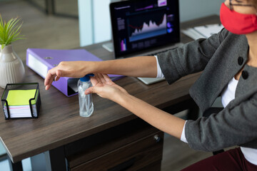 Mixed race woman disinfecting her hands in an office