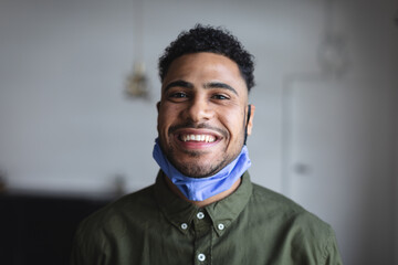 Portrait of middle eastern man with lowered face mask against grey background