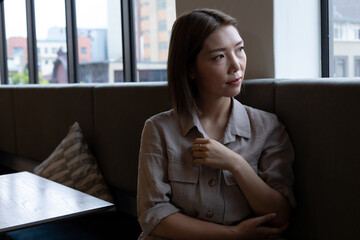 Asian woman looking out of window in creative office cafeteria