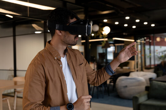 Mixed race businessman wearing virtual reality headset in creative office
