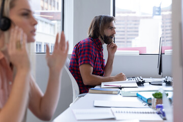 Obraz premium Caucasian man and woman wearing phone headset in modern office