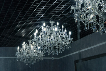 Luxury large crystal chandeliers with candle-shaped light bulbs on a dark background