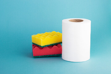 White kitchen cleaning cloths and colorful sponges on a blue background