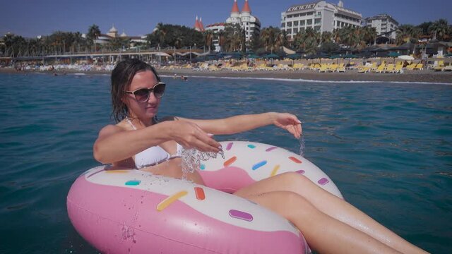 A beautiful woman in bekini rests on the sea. A young woman in sunglasses, swims on an inflatable circle.