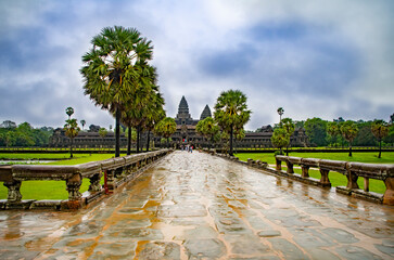  Angkor Wat-largest temple in the world. It is raining. Tourists walk around the temple