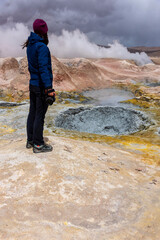 Obraz premium Woman with a camera photographing some mud pits with volcanic activity in the Andean Highlands, Bolivia.
