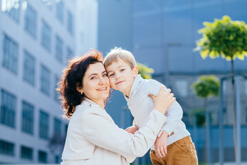 Mothers support and care. Autumn sunny day.Close up portrait of mom and her son on street. Mother...
