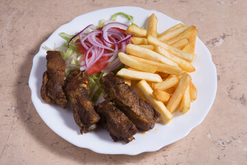 Half rack of barbecue pork ribs with french fries.