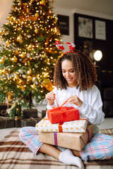 Fototapeta na wymiar Happy lady with gifts near the Christmas tree. Young woman posing with presents in Christmas interior design. Fashion, celebration, holidays concept.