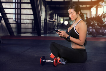 Fototapeta na wymiar Sports women use their smartphones to select music during gym workouts.