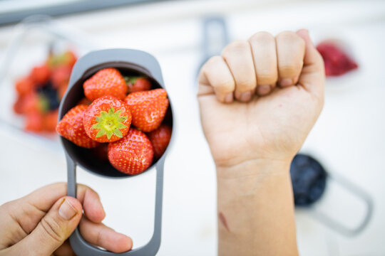 Female hands holding measuring cup full of fresh strawberries
