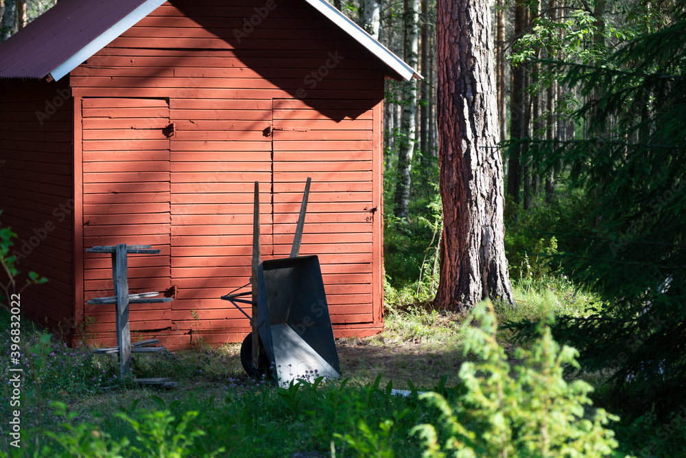 Wall mural A small red house in the woods and an old wheelbarrow 