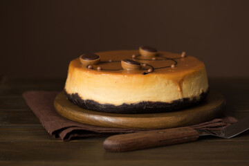 Cheesecake with salted caramel on brown  background. Copy space for text.