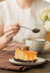 Woman drinking tea with Cheesecake with salted caramel on brown  background. Copy space for text.