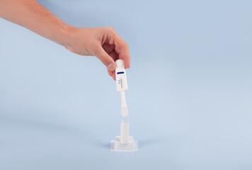 Man holding oral HIV test on blue background.