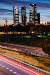 Cuatro Torres Business Area in Madrid Spain with electricity cables across them with graffitis and highway at sunset